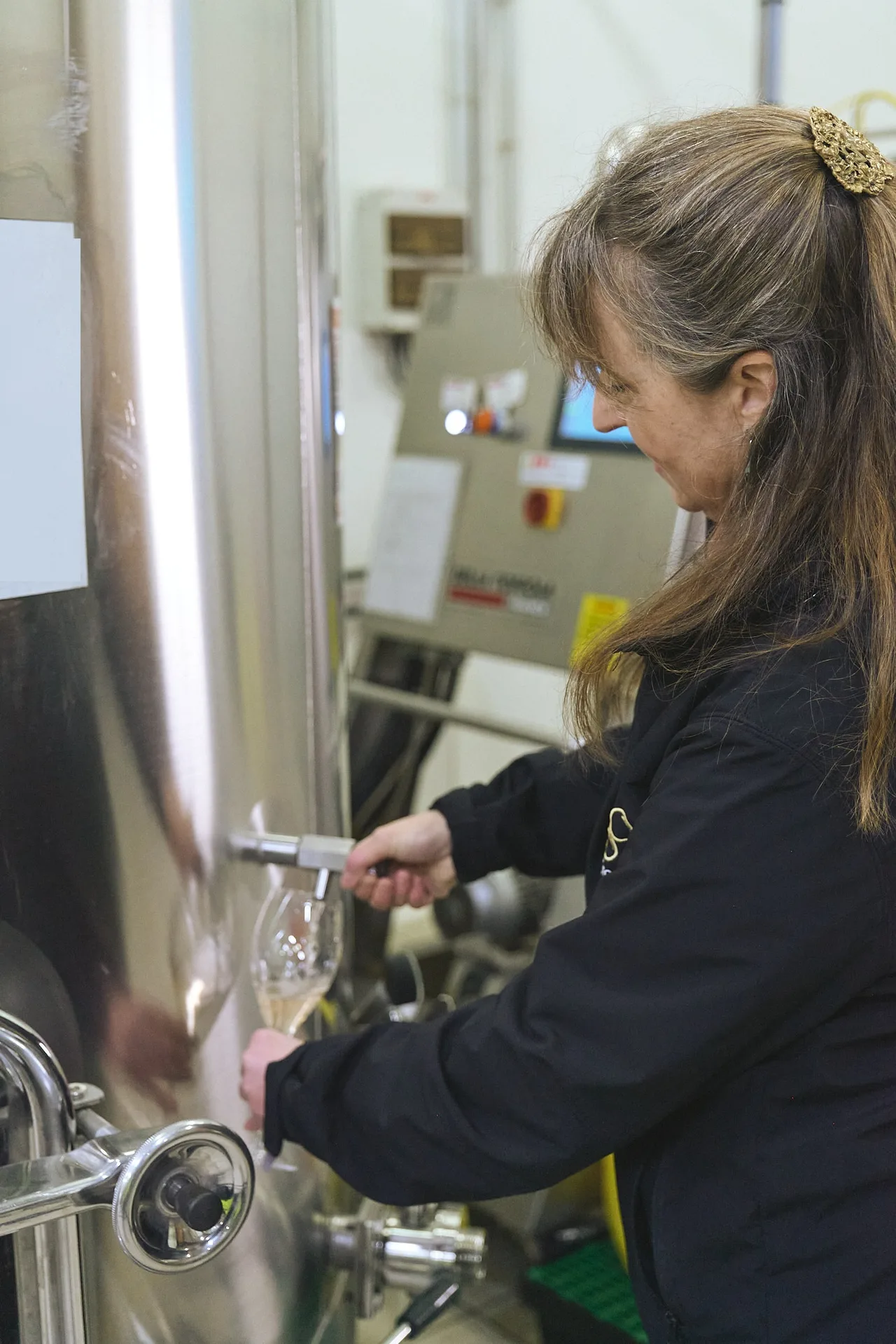 Œnologue SVPé prélevant un verre de vin au robinet d'une cuve inox
